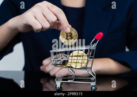 Femme tenant quelques morceaux de jeton Bitcoin doré dans le panier Banque D'Images