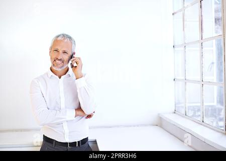 J'ai eu de bonnes nouvelles pour vous. Portrait d'un beau homme d'affaires mature utilisant son téléphone portable à l'intérieur. Banque D'Images