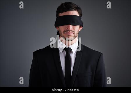 Si je ne l'ai pas vu, cela s'est-il produit ? Photo studio d'un jeune homme d'affaires portant un bandeau sur fond gris Banque D'Images