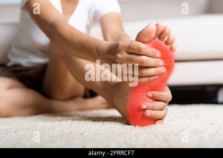 Douleur de pied, femme asiatique sentant la douleur dans son pied à la maison, femme souffrant de douleur de pieds utiliser le massage de main détendre muscle de la plante à l'intérieur de la maison, lui Banque D'Images