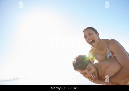 Les meilleurs jours de notre vie. Un jeune homme donnant à sa petite amie un pigegyback sur la plage. Banque D'Images