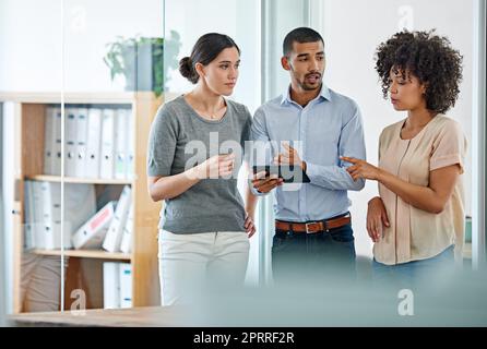 Jeunes professionnels avisés. Collègues de bureau ayant une discussion sur une tablette numérique Banque D'Images