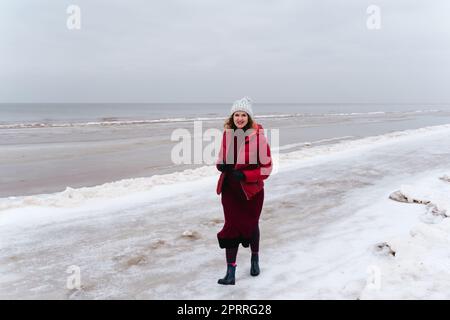 Promenade d'hiver le long de la mer, une femme marche et sourit Banque D'Images