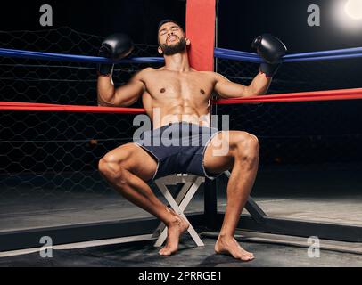 Boxeur fatigué dans le ring de boxe ou une arène, fond sombre et spot pour la lutte, la compétition de combat mma ou un match sportif. Homme fort avec des gants de boxe pour l'entraînement, l'exercice ou l'entraînement physique Banque D'Images