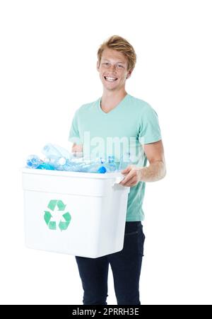 Prenez le temps de recycler. Un jeune homme heureux à tête rouge tenant un bac de recyclage rempli de bouteilles en plastique vides. Banque D'Images