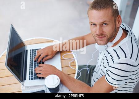 Vous ne savez jamais quand l'inspiration va frapper. Photo en grand angle d'un beau jeune homme travaillant sur un ordinateur portable à l'extérieur Banque D'Images