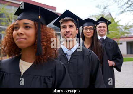 Ils se dirigeaient vers le haut. Les étudiants diplômés d'une université se tenant debout dans une rangée regardant vers le haut Banque D'Images