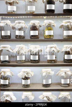 vue avant des récipients en verre contenant des feuilles de plantes séchées et des condiments avec des étiquettes blanches vides sur les tablettes de garde-manger Banque D'Images