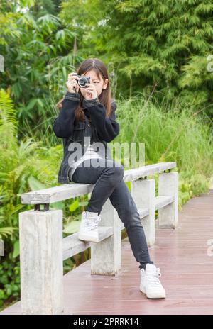 Jeune fille asiatique prenant des photos à l'extérieur Banque D'Images