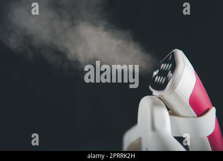 Gros plan sur la centrale vapeur électrique lorsqu'elle est chaude et que de la vapeur s'échappe sur la table à repasser Banque D'Images