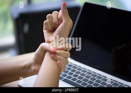 Une jeune femme a blessé son poignet pendant longtemps en utilisant un ordinateur portable. Gros plan Banque D'Images