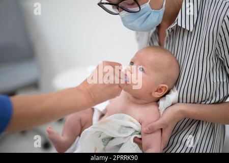 Pédiatre administrant la vaccination orale contre l'infection à rotavirus à petit bébé en présence de sa mère. Soins de santé pour enfants et prévention des maladies Banque D'Images