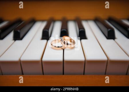 Anneaux de mariage dorés sur les touches du piano. Banque D'Images