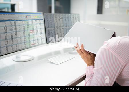 Un homme d'affaires embarrassé se hante sous un ordinateur portable Banque D'Images