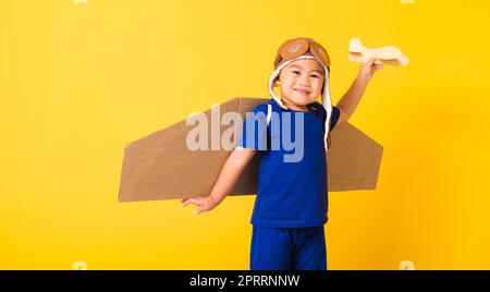 Enfant petit garçon sourire porter un chapeau de pilote jouer et des lunettes avec ailes d'avion en carton Banque D'Images