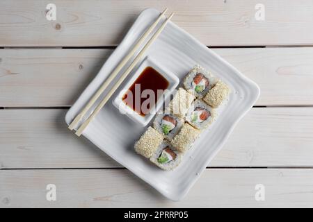 Maki Sushi - rouler avec du saumon fumé, du fromage à la crème, de la salade feuille et de l'avocat à l'intérieur. Sésame à l'extérieur. Banque D'Images