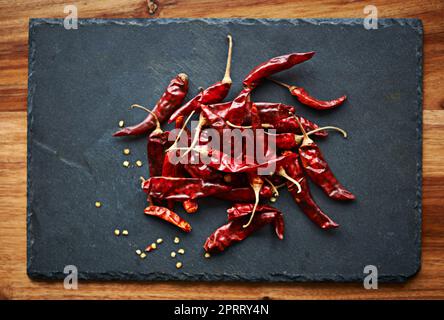 Ajoutez un peu de feu à votre nourriture. Photo en grand angle de piments rouges séchés sur un comptoir de cuisine Banque D'Images