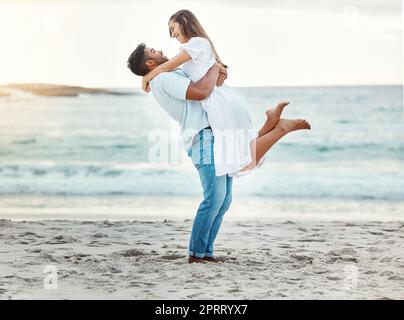 Homme à la plage de remontée femme avec amour, sourire avec le soleil se coucher sur l'horizon ou l'arrière-plan. Les jeunes couples se rendent à l'océan en vacances, heureux avec un coucher de soleil sur la mer ou des vagues en toile de fond. Banque D'Images