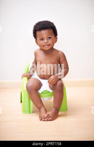 C'est un gros garçon. Un adorable petit garçon assis sur un siège d'entraînement en pot. Banque D'Images