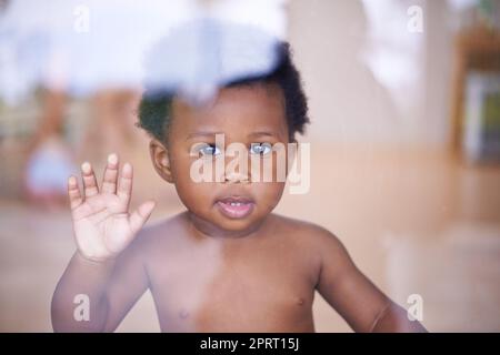 Prêt à vous familiariser avec le monde. Portrait d'un bébé garçon mignon regardant par la fenêtre Banque D'Images