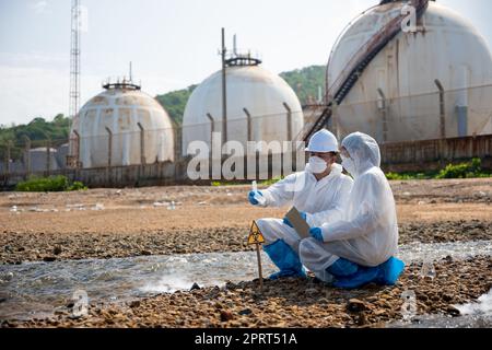 Le biologiste porte un vêtement de protection et un masque pour recueillir des échantillons d'eaux usées provenant de l'industrie, de l'environnement problématique, de l'écologiste pour inspecter les poissons morts Banque D'Images