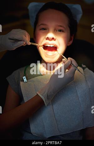 Sous la lumière des dentistes. Gros plan d'une jeune fille ayant un examen chez le dentiste Banque D'Images