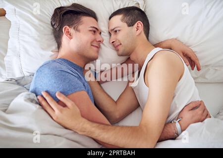 Je pourrais mentir ici toute la journée. un jeune couple gay se détendant au lit Banque D'Images