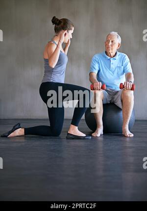 Aider mes patients à récupérer est ma seule priorité : un physiothérapeute travaillant avec un homme âgé. Banque D'Images