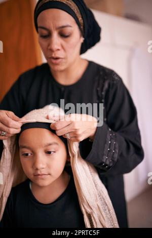 Les traditions sont un lien fort : une mère qui aide sa fille à mettre un foulard Banque D'Images