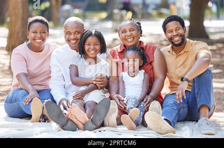 L'amour, le sourire et la famille noire se liant à l'extérieur, se détendre et heureux, s'amuser sur un pique-nique dans un parc ou une forêt. Portrait d'une grande famille liant et profitant d'un après-midi ensoleillé avec les grands-parents Banque D'Images