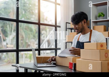 Idées d'affaires en ligne homme asiatique vendant des choses en ligne tenant des boîtes de colis se préparant à livrer aux clients avec joie Banque D'Images
