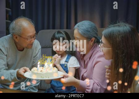 les grands-parents et la mère célèbrent la fête de chant d'anniversaire avec le gâteau de la petite-fille Banque D'Images