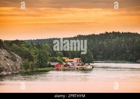 Suède.Beaucoup de belles chalets en bois rouge suédois Maisons sur la côte des îles Rocheuses en soirée d'été.Paysage de lac ou de rivière. Banque D'Images