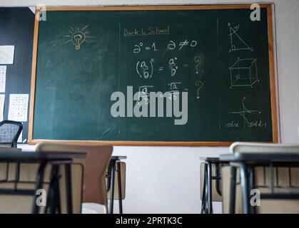 Salle de classe vide avec chaises, bureaux d'école primaire et tableau noir Banque D'Images