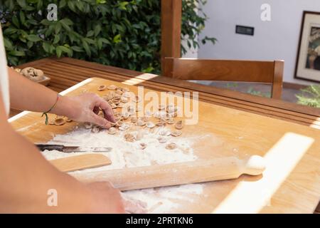 Femme fabrique des pâtes italiennes du sud orecchiette en plein air dans la cour de la maison de près. Pâtes maison fraîches traditionnelles de la région des pouilles. Régime méditerranéen Banque D'Images