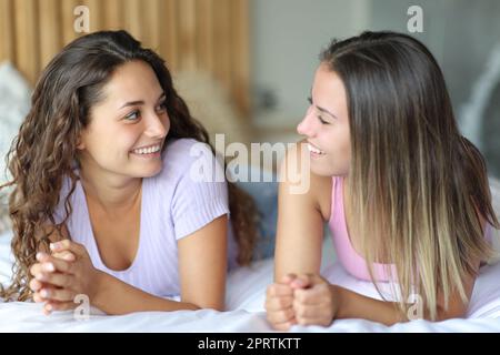 Deux amis heureux parlant allongé sur le lit dans une chambre Banque D'Images