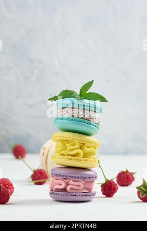 Pile de macarons multicolores et de framboises rouges sur fond blanc Banque D'Images