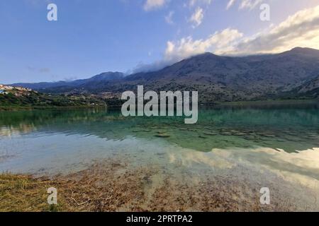 Vue sur le magnifique lac de Kournas avec eau turquoise claire pendant le coucher du soleil. Reflet du soleil dans l'eau du lac de Kournas pendant le coucher du soleil. Banque D'Images