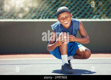 Enfant avec un bracelet d'aide sur une blessure de genou par des sports à l'extérieur sur un terrain de basket-ball touchant son bandage. Garçon avec un plâtre médical blessé par accident lors de la formation ou de la pratique pour un jeu. Banque D'Images