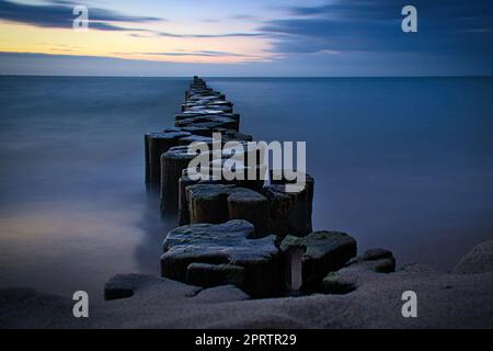 Groynes qui dépassent dans l'horizon dans la mer Baltique. Exposition longue durée avec couleurs muettes Banque D'Images