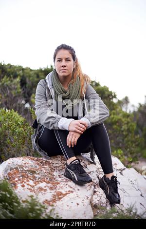 Prendre une pause de sa promenade dans la nature. Portrait d'une jeune femme attirante prenant une pause pendant la randonnée Banque D'Images