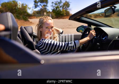 J'adore la route. Une jeune femme qui conduit dans une voiture de sport. Banque D'Images