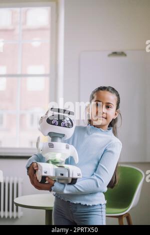 Portrait d'une fille portant un robot social debout dans un laboratoire d'innovation Banque D'Images