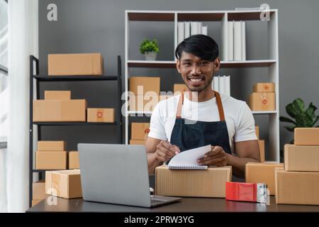 Idées d'affaires en ligne homme asiatique vendant des choses en ligne tenant des boîtes de colis se préparant à livrer aux clients avec joie Banque D'Images