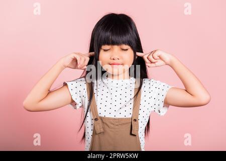 Petit enfant asiatique de 10 ans Fermez ses oreilles avec les doigts et les yeux Banque D'Images