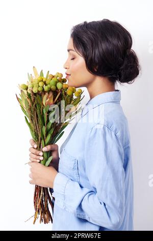 L'arôme des natures. Studio photo d'une jeune femme ethnique attrayante tenant un bouquet de fleurs Banque D'Images