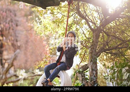 Des journées d'été insouciantes d'une enfance idyllique. Un préadolescent balançant sur une balançoire de pneu dans le jardin. Banque D'Images