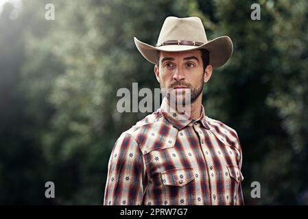 Les cow-boys ont aussi du style. Un beau cowboy portant une chemise à carreaux et stetson Banque D'Images