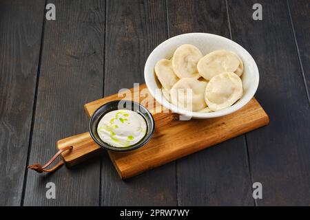 Bol de boulettes au caillé et à la crème sure sur une planche à servir en bois Banque D'Images