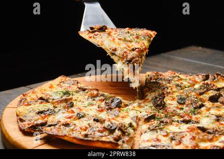 Morceau de pizza fine pâte avec champignons sur la spatule Banque D'Images